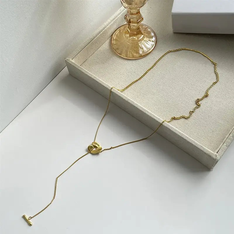Collier pendentif à superposition géométrique doré pour femmes, présentant une chaîne aux tons dorés avec un pendentif central en forme de nœud et une attache à t-bar.