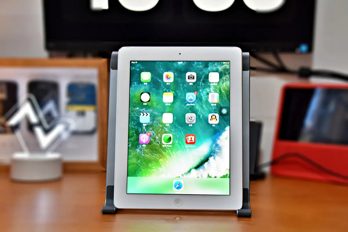 White iPad with a sleek minimalist design and rounded corners displayed on an Orico portable aluminum laptop stand and desktop riser.