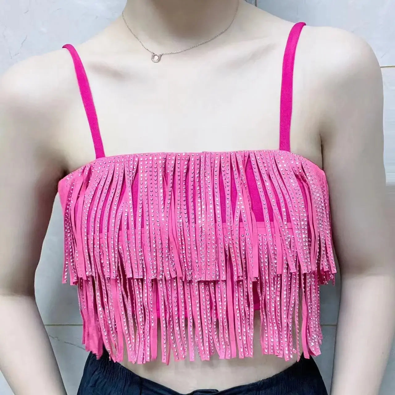 Haut court rose vif à franges, avec fines bretelles et ornements en strass scintillants, assorti à une mini-jupe taille haute à franges en strass.