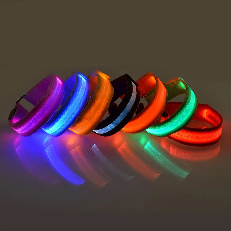 Un conjunto de seis brazaletes LED para correr en colores vibrantes: morado, azul, naranja, negro con franja blanca, rojo y verde, con luces de seguridad recargables por USB.