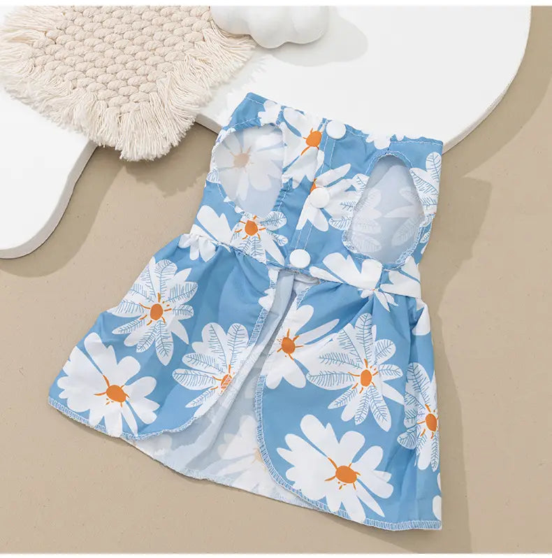 A light blue floral dog princess dress with a white daisy pattern featuring orange centers and cut-out shoulder details with a decorative bow.