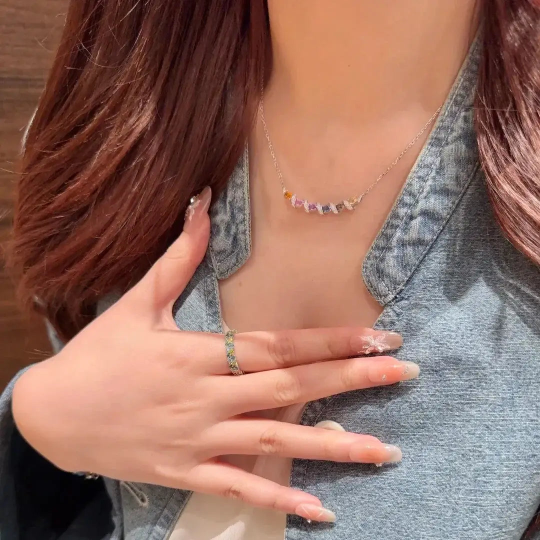 Un collier délicat en chaîne or surmontée d'argent, avec un pendentif géométrique multigemme orné de pierres précieuses facettées colorées.