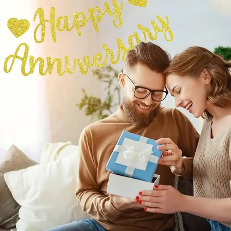 Blue gift box with white ribbon and bow featured as an anniversary banner party decoration glitter sign.
