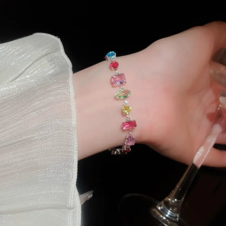 A delicate silver bracelet with a vibrant array of colorful faceted zircon crystals in blue red pink green and yellow for a colorful zircon crystal gold plated necklace collection.