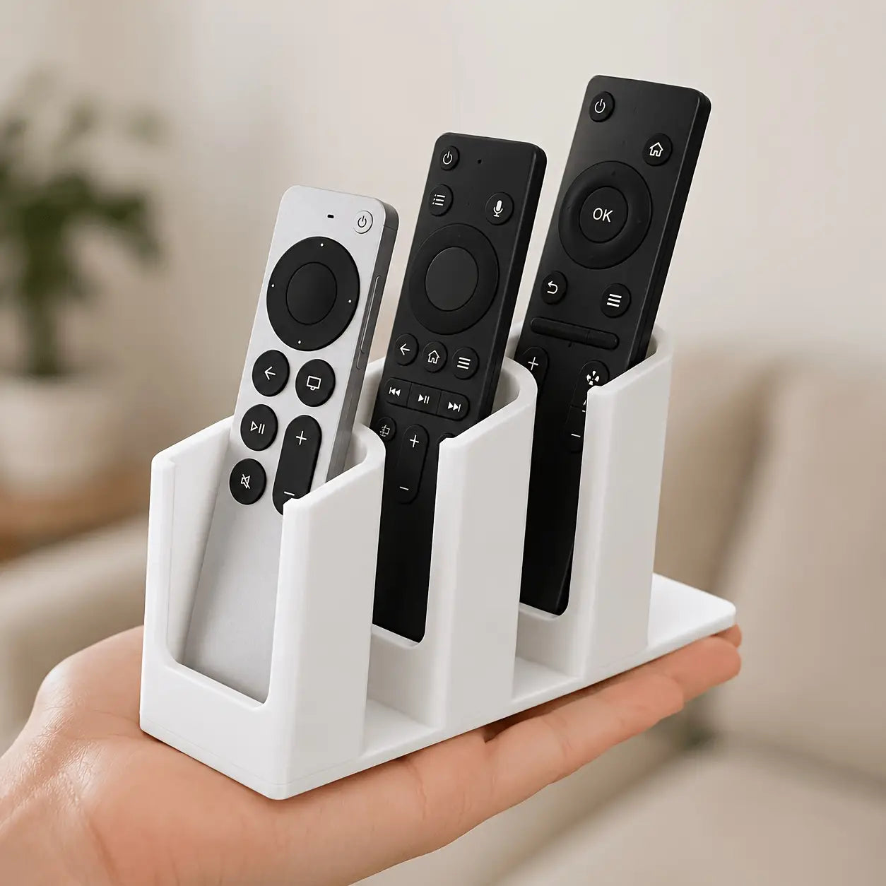 White plastic remote control organizer with three slots holding various remotes for convenient storage and accessibility.