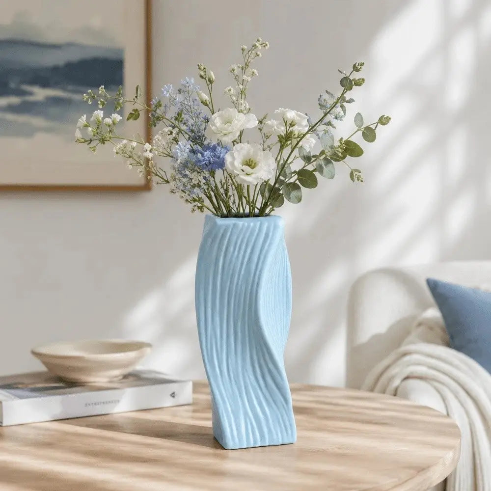 A light blue ceramic Nordic wave plastic flower vase with a sleek twisted design and vertical ridges for aesthetic home decor.