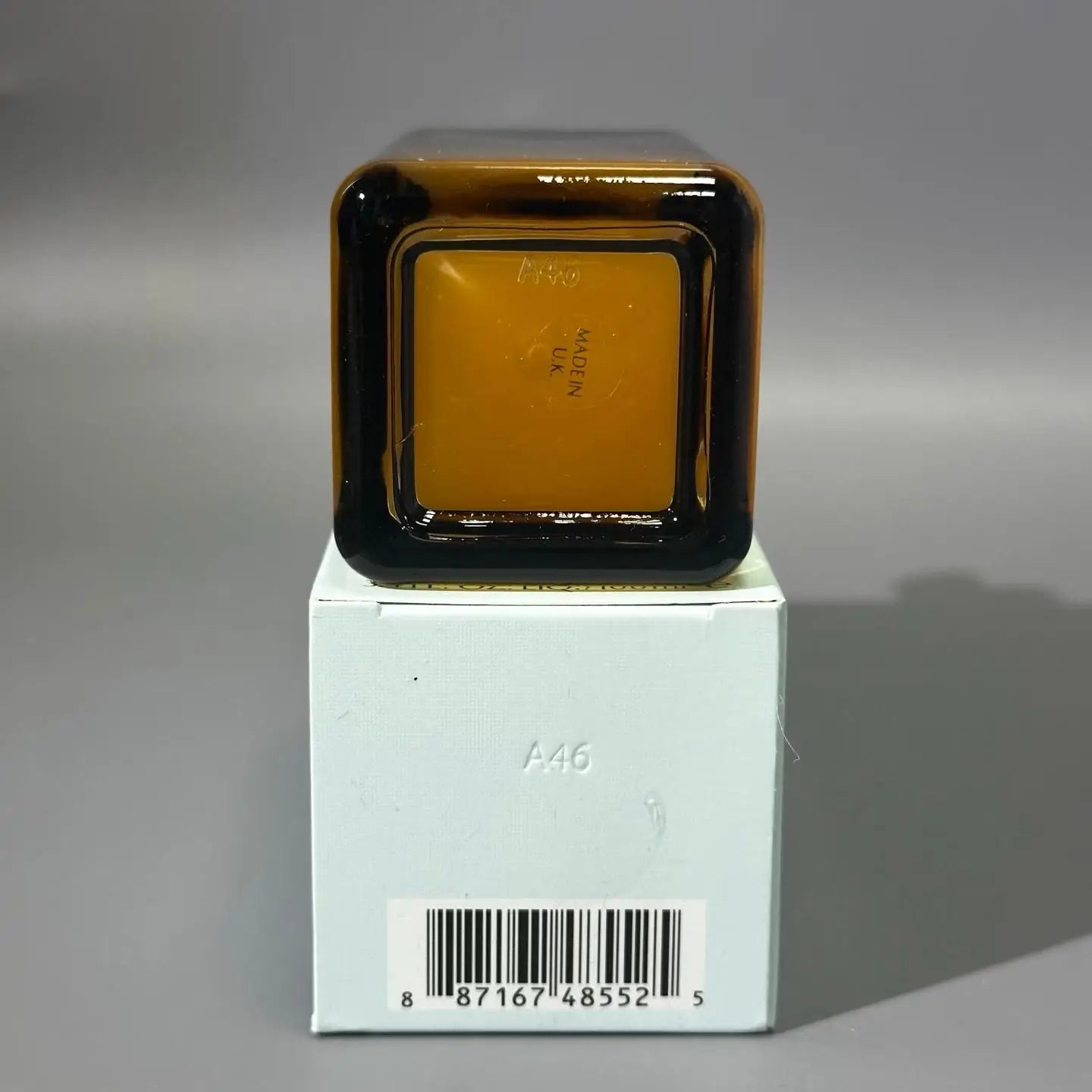 une bouteille carrée en verre ambré avec une bordure noire, étiquetée « Made in UK », montrée depuis la base d’un sérum pour le visage 100 ml, produit de soins pour le visage