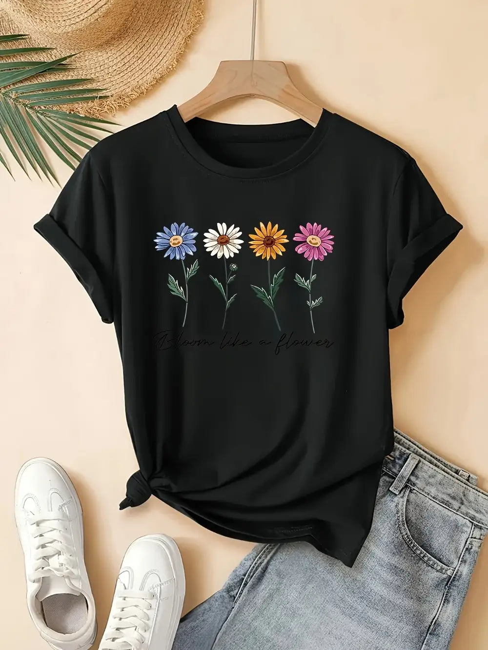 camiseta casual de manga corta negra con estampado floral colorido, que presenta cuatro margaritas en azul, blanco, amarillo y rosa.