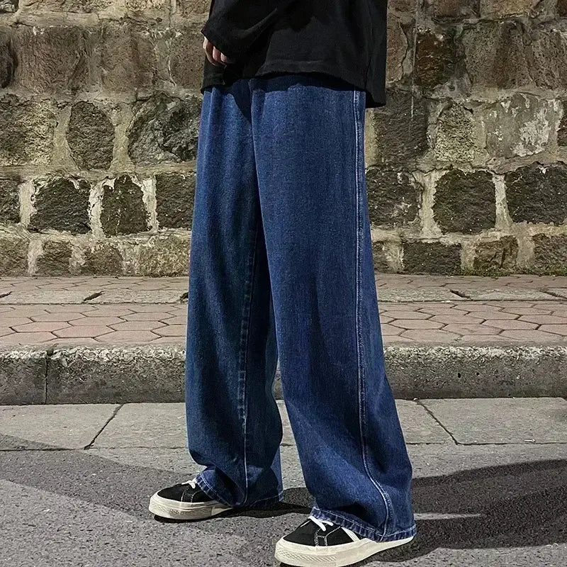Jeans en denim bleu foncé à jambes larges pour hommes, avec une coupe ample et décontractée et des surpiqûres visibles, parfaits pour un style streetwear coréen.