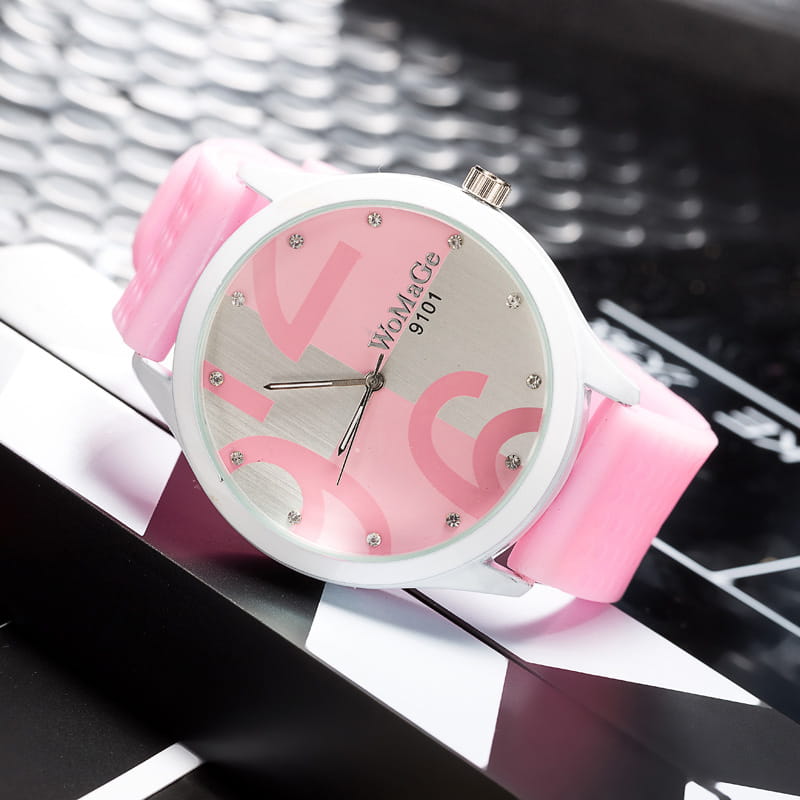 Womage silicone quartz women sports watch with a pink silicone strap white face featuring pink abstract lettering and small crystal accents.
