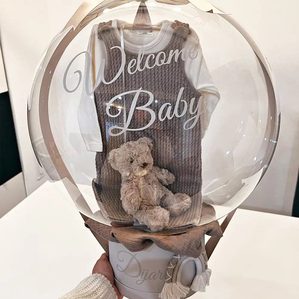 Ein gemütliches graues, gestricktes Babykleidungsstück mit langen Ärmeln, präsentiert in einer klaren, kugelförmigen Ballonumhüllung, die mit einem Baby-Party-Ballonaufkleber für 36-Zoll-Bobo-Ballons personalisiert ist