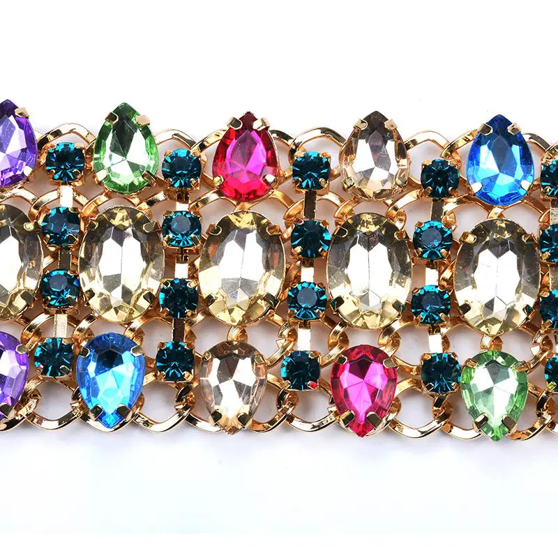 Un collier ras du cou en cristal arc-en-ciel à multiples brins, éclatant, présentant des montures en métal à tons dorés avec des strass colorés en forme de goutte, d’ovale et de rond.