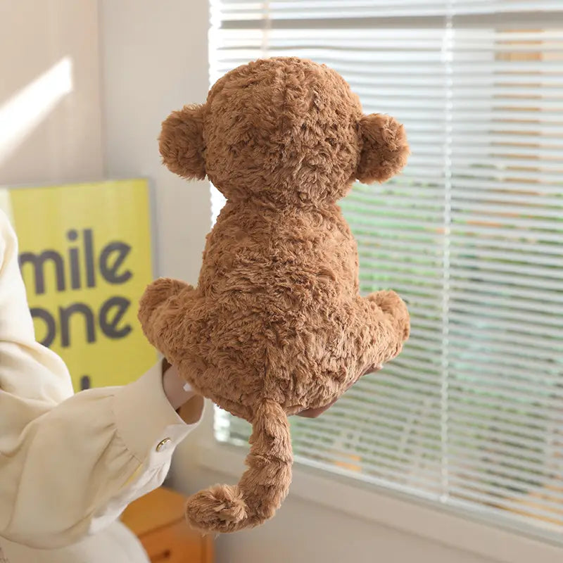 A plush stuffed animal toy 25cm featuring a tan-colored monkey with soft curly fur and rounded ears.