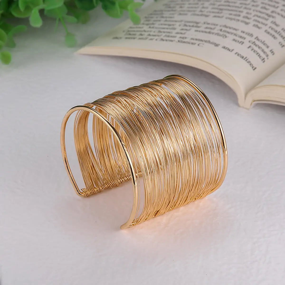 Bracelet manchette en fil plaqué or présentant un design en fil multi-brins ton sur ton, avec une apparence superposée épurée.