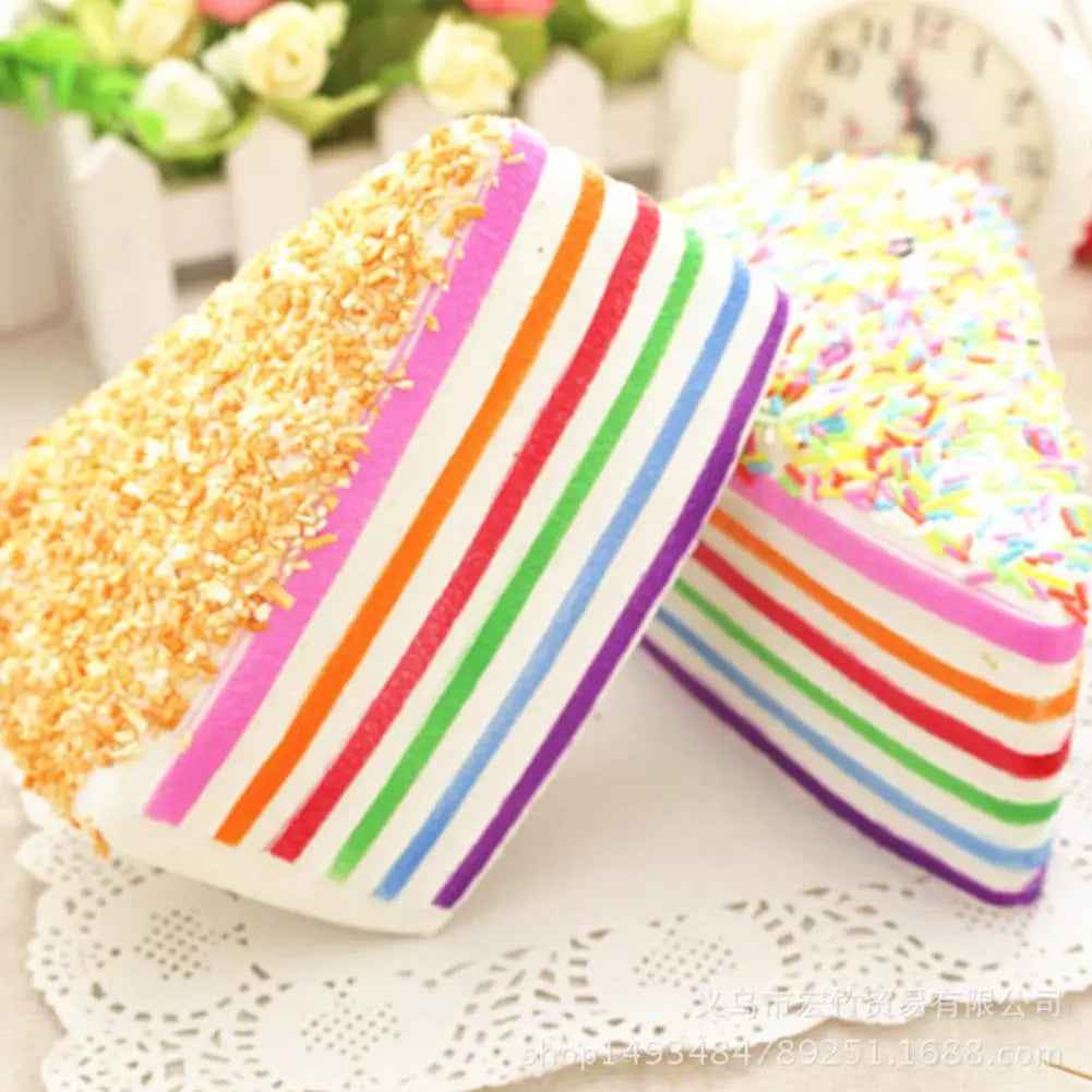 Jouet antistress à gâteau arc-en-ciel à rebond lent, en silicone, avec un design de gâteau éponge superposé rayé arc-en-ciel, avec des vermicelles colorés et des flocons de coco sur le dessus.