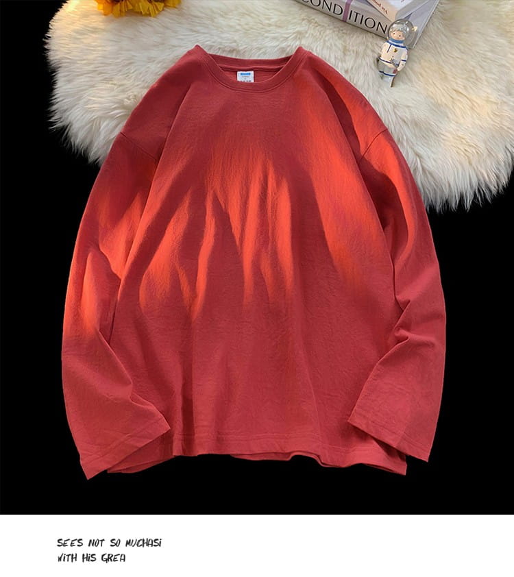 A soft coral-red oversized long sleeve blank t-shirt with a relaxed fit crewneck and subtle fabric texture.