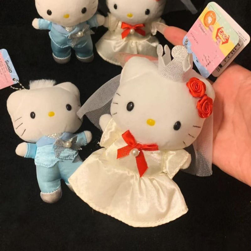 Porte-clés en peluche couple de mariage Hello Kitty, représentant une figurine de mariée en peluche Hello Kitty blanche portant une robe de mariage en satin, avec un nœud de ruban rouge, un voile en dentelle et un accessoire de cheveux en forme de rose rouge.