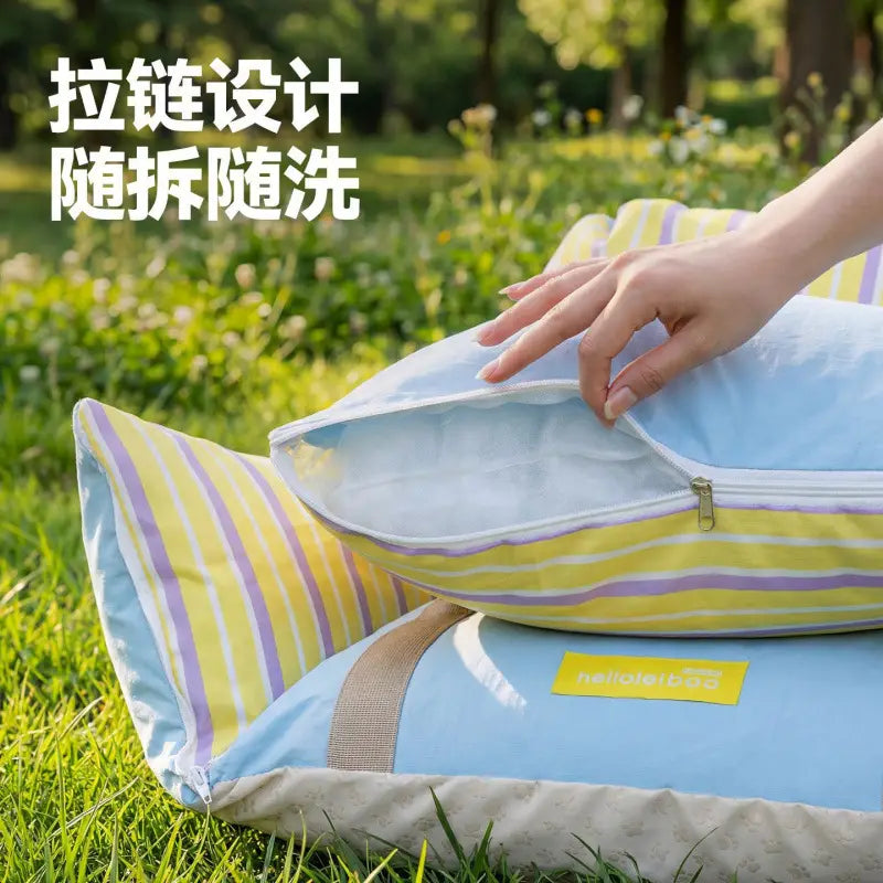 Taie d’oreiller à rayures jaune et violette avec fermeture à glissière, reposant sur le coussin bleu clair du petit siège de voiture pour chien et du lit de voyage