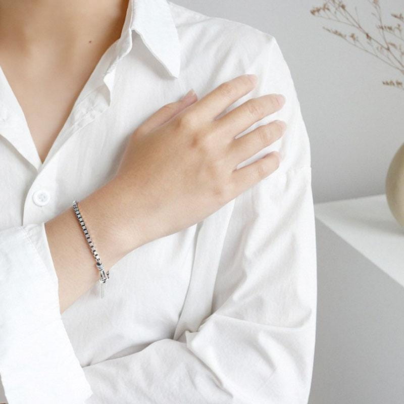 L’image présente un bracelet de charme en métal géométrique ton argent pour couples, doté d’un design de maillons à emboîtement élégant et d’une petite fermeture.
