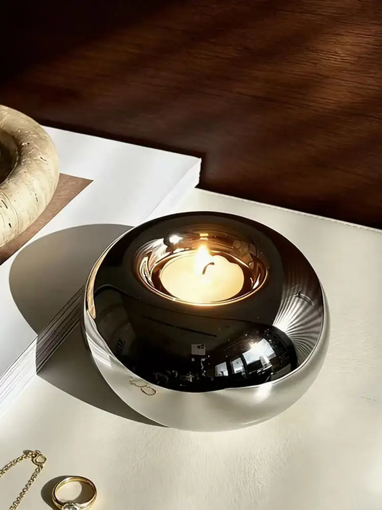 Silver ceramic sphere candle holder featuring a shiny metallic finish with a reflective black interior and subtle radial grooves.