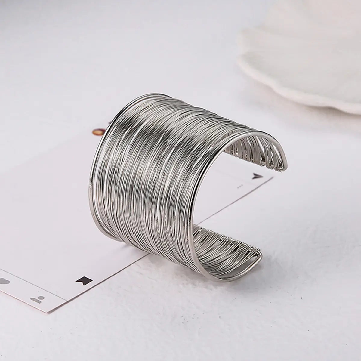 Bracelet manchette en fil argenté avec un design texturé multicouche présenté depuis le côté arrière, alliant savoir-faire élégant et style contemporain