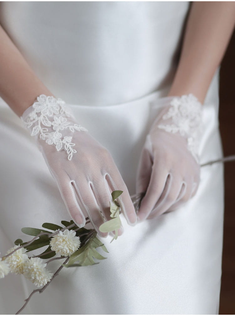 white lace bridal gloves with delicate floral embroidery made of tulle applique worn with a wedding gown
