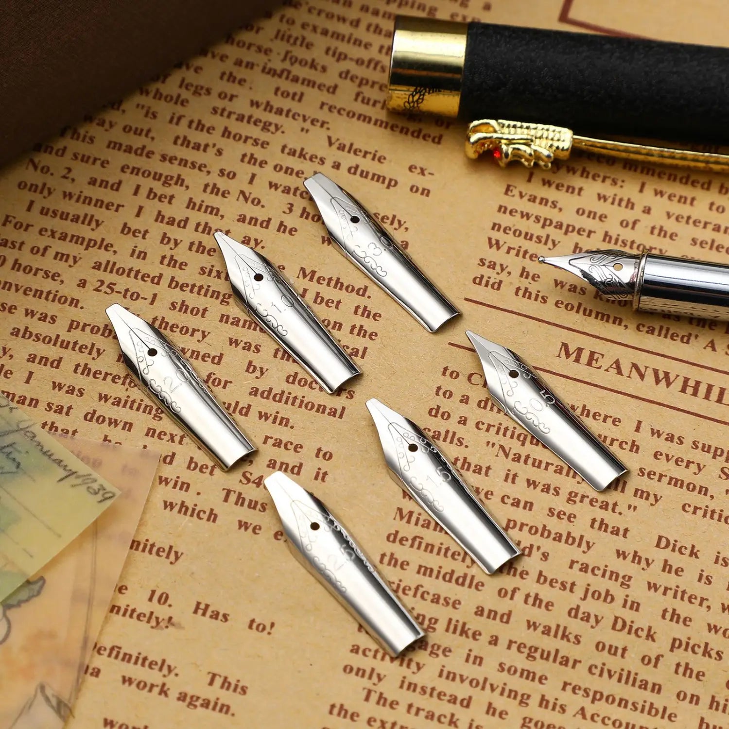 Silver stainless steel fountain pen nibs with intricate engraved designs displayed alongside a black and gold stainless steel fountain pen nib set.