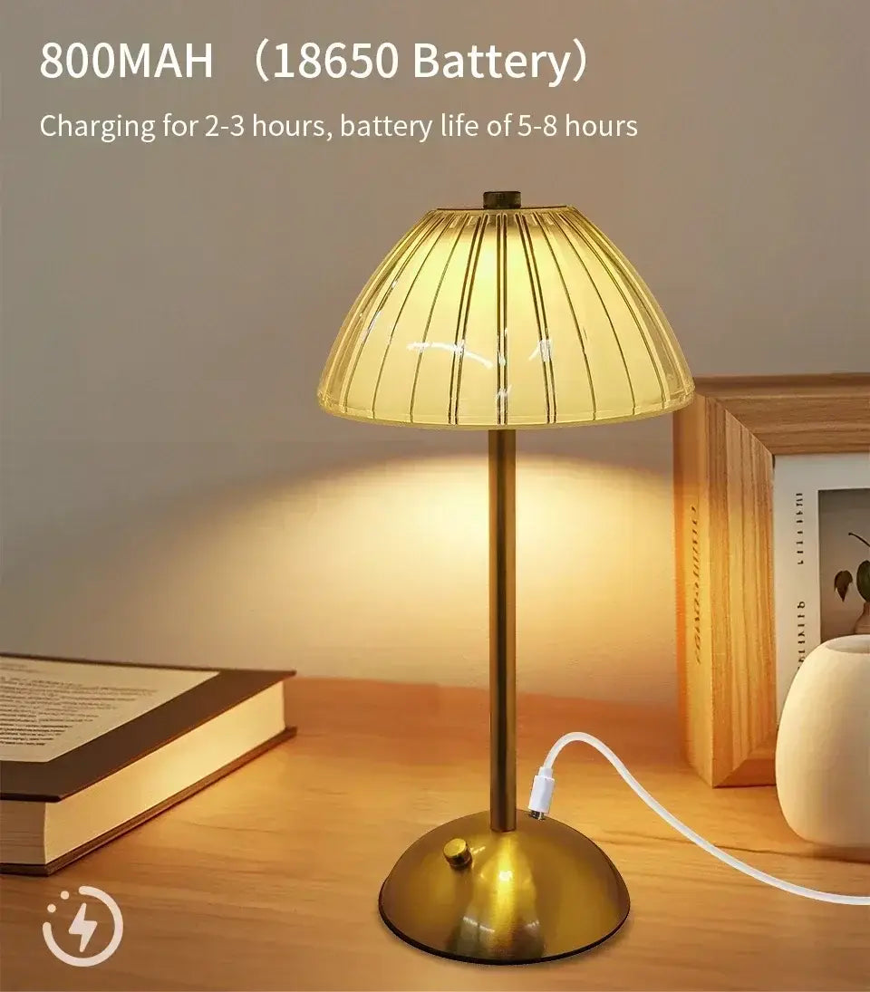 Eine warm getönte wiederaufladbare Tischlampe mit Messing-Finish, geripptem Glasschirm und einem 800-mAh-Akku als tragbare Lichtquelle