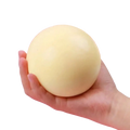 A soft pale yellow spherical squishy ball held in hand stress relief anti-anxiety sensory fidget toy