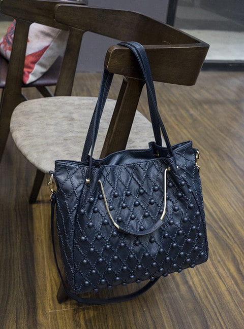 Bolso de hombro de cuero acolchado azul oscuro con herrajes de tono plateado, con diseño con tachuelas y un compartimento interior amplio.