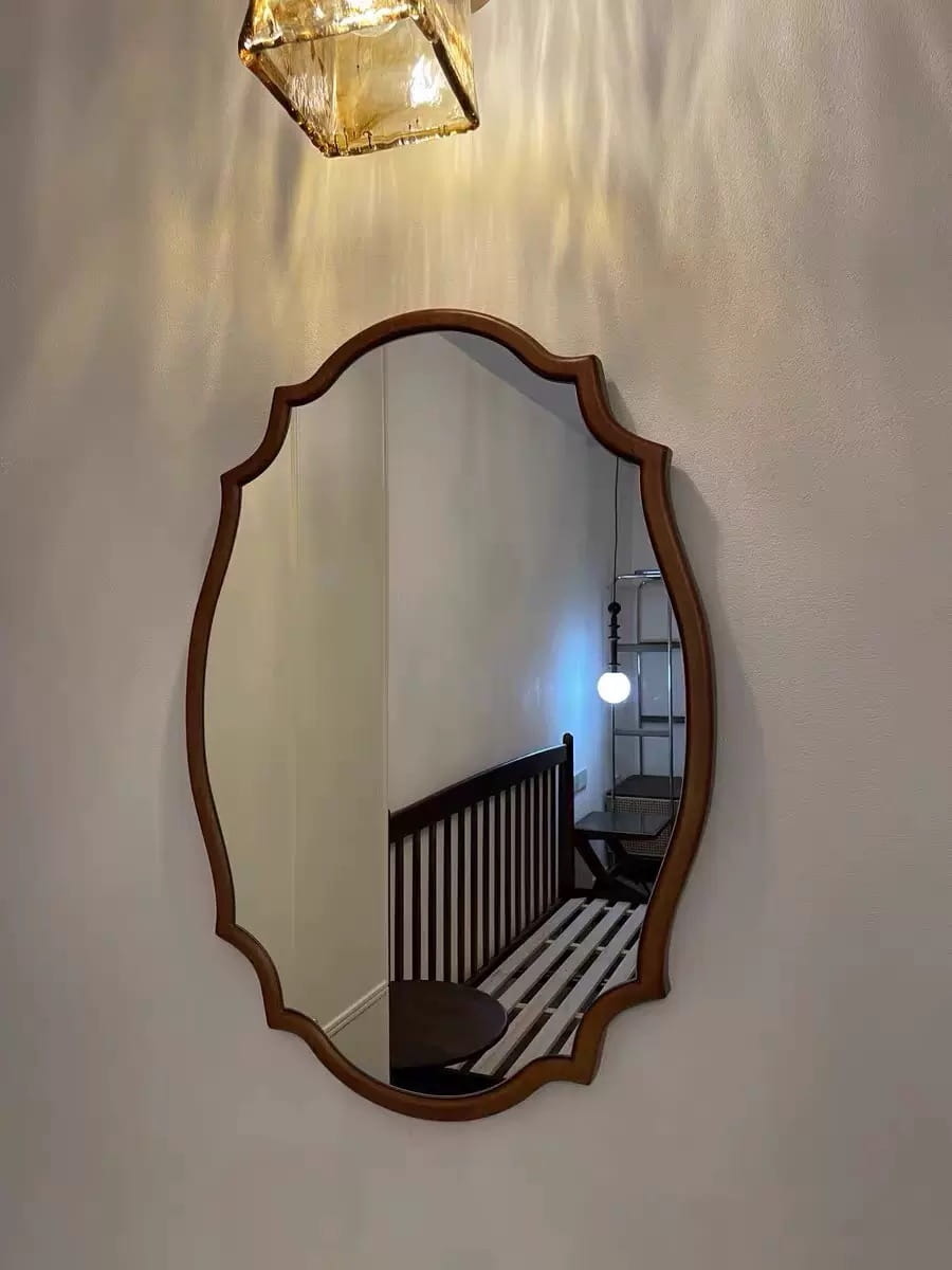 Miroir de salle de bains ovale à cadre en bois, bord à volutes, tons brun chaud, présentant un style classique ornemental, adapté à une décoration murale.