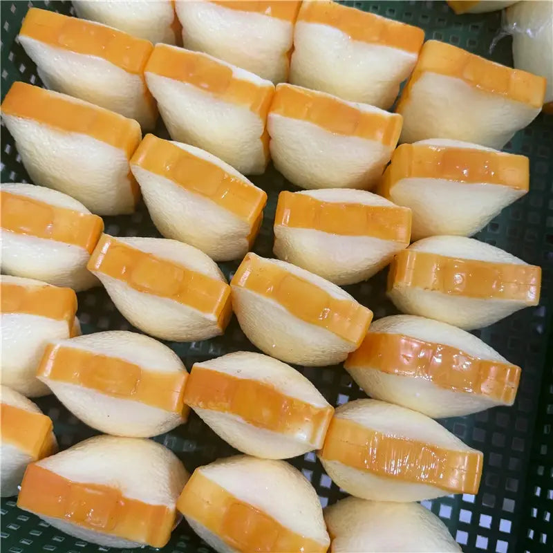 Butterstick als ASMR-Sensory-Squishy-Spielzeug, geformt wie weiß- und orangefarbene geschichtete Dumplings mit einem glänzenden, leicht transparenten Aussehen.