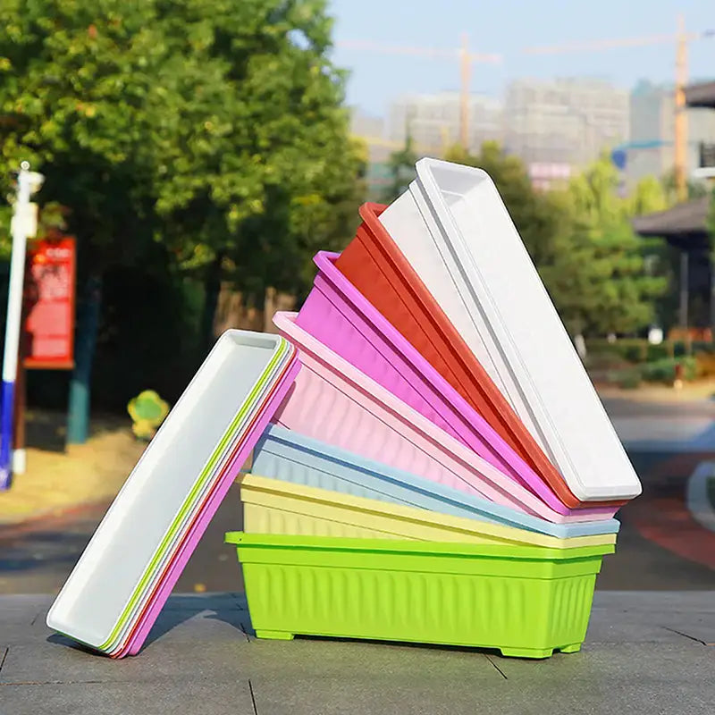 Un apilamiento de macetas rectangulares de plástico para plantación de colores vivos en blanco, rosa, naranja, amarillo y verde lima, para macetas de plantas, úsese.