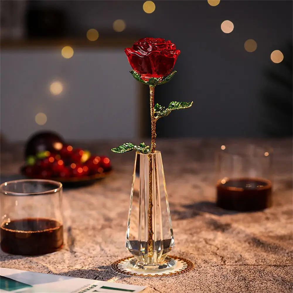 A vibrant red crystal-encrusted rose with a gold-toned stem and green leaves stands elegantly in a clear faceted glass vase as a crystal glass rose gift for Valentine’s Day.