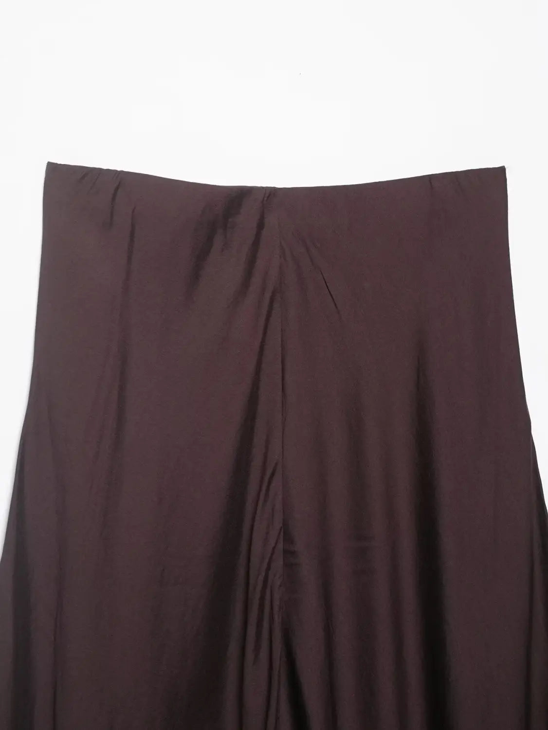 Ein dunkelbrauner Satin-Plisseerock im Midi-Format mit hoher Taille und einer fließenden A-Linien-Silhouette mit glattem, leicht glänzendem Stoff und dezenten vertikalen Falten.