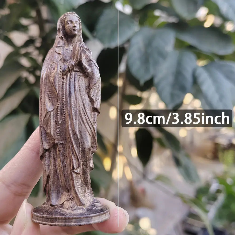 Statuette de la Vierge Marie en bois sculpté à la main, finement détaillée, avec une robe drapée et les mains jointes en prière.