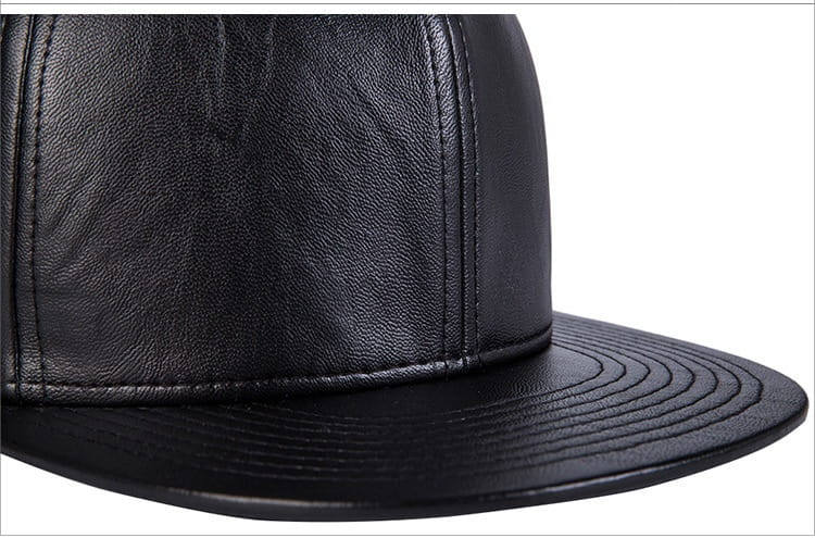 Gorra tipo snapback de cuero negro con visera plana, con paneles cosidos y un material de cuero sintético negro.