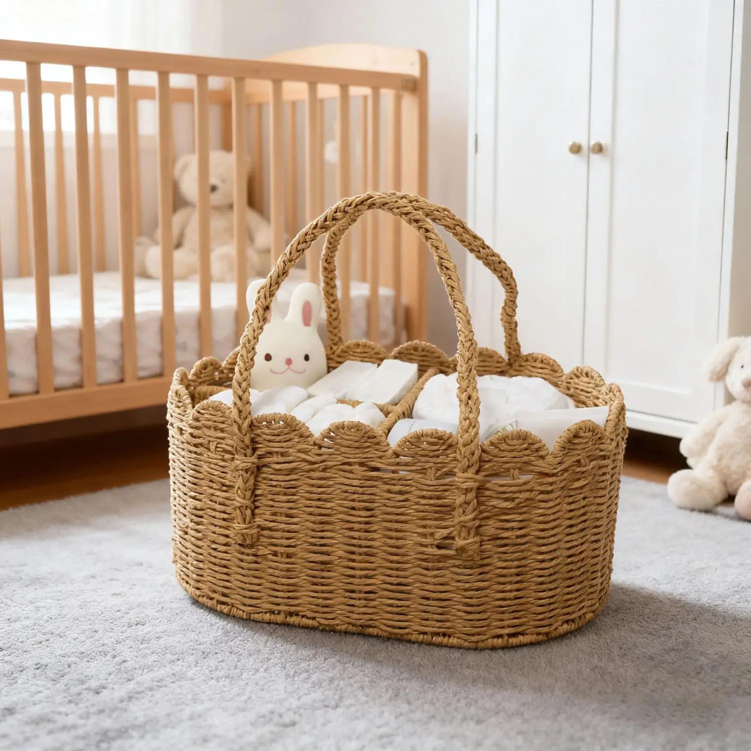 Natürlich geflochtener Wickelkorb aus Weidengeflecht mit geschwungenen (gezackten) Kanten und geflochtenen Griffen, der weiße Windeln und ein flauschiges Kaninchen-Spielzeug mit herausnehmbaren Trennwänden trägt.