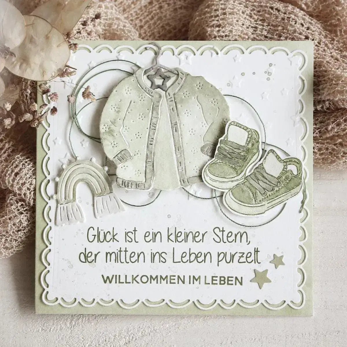 eine cremefarbene Babykarte mit einer strukturierten bestickten Jacke und passenden Sneakers in sanftem Salbeigrün, die Oster-Ei-Hasen-Babyschneidvorlagen präsentiert.