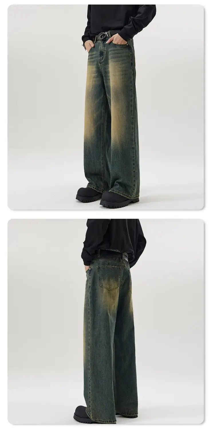 ワイドレッグのフィットで、色褪せたダメージ風のルックを特徴とするダメージ加工ヴィンテージ風バギー系メンズデニムジーンズ。デニム素材に控えめな黄みがかったグリーンの染めアクセントがある。