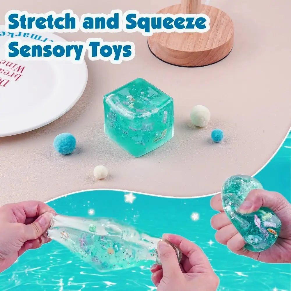 Ein durchscheinender türkisfarbener, würfelförmiger Fidget-Toy, gefüllt mit schimmernden silbernen Flakes und mit eingearbeiteten Motiven von Meeresbewohnern; entworfen als ozeanmuschelartiger Fidget-Toy, weicher Würfel-Stressball.