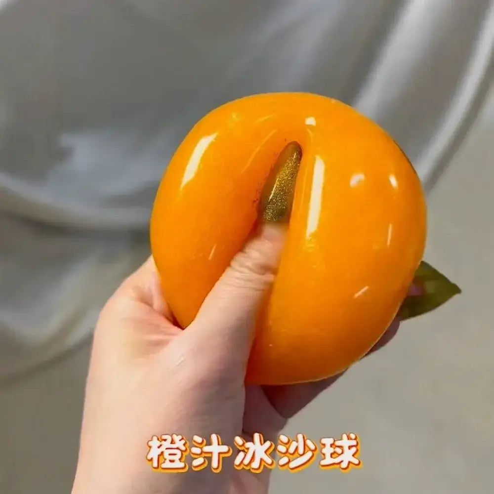 Vibrant orange glossy peach-shaped orange slushy squishy stress relief toy with a golden glittery stem shown from the front.