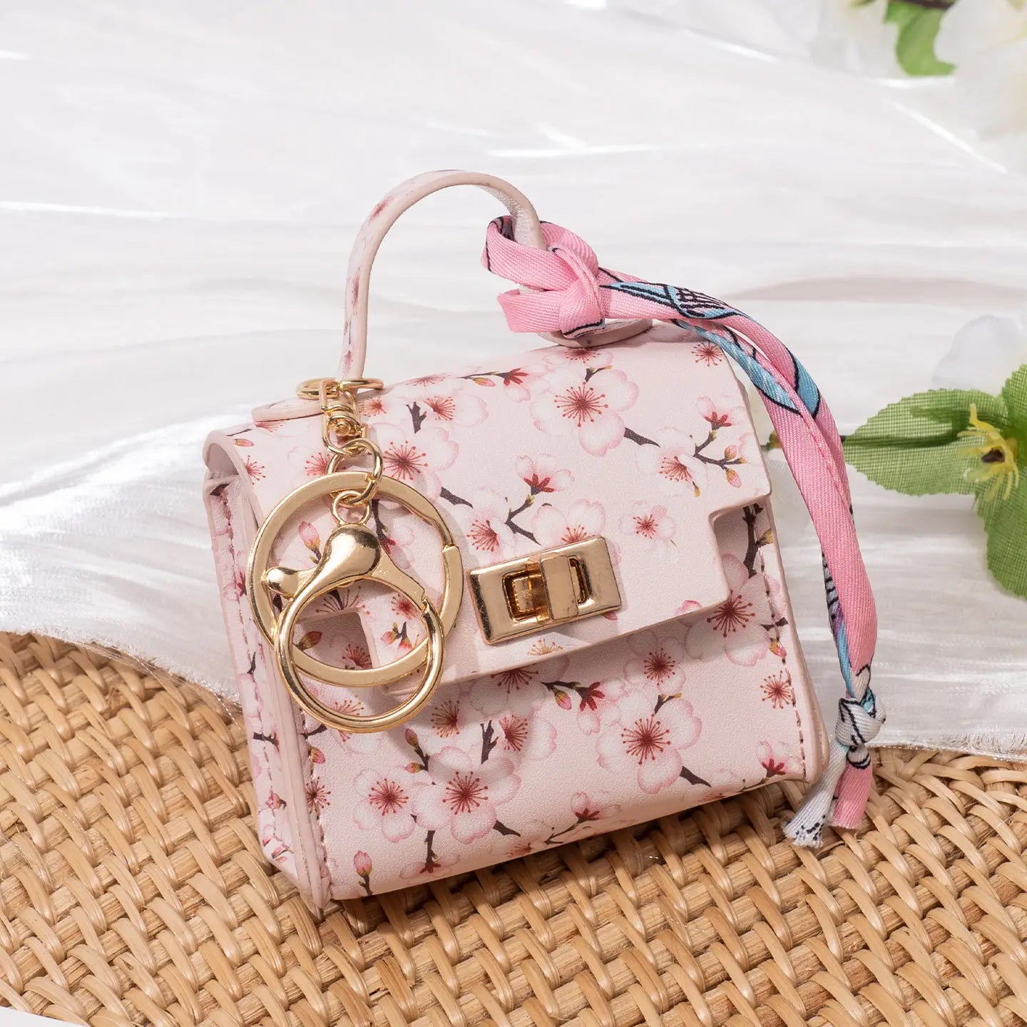 Miniature handbag keychain featuring a pink floral silk scarf purse with gold-tone hardware and a matching ribbon keychain.
