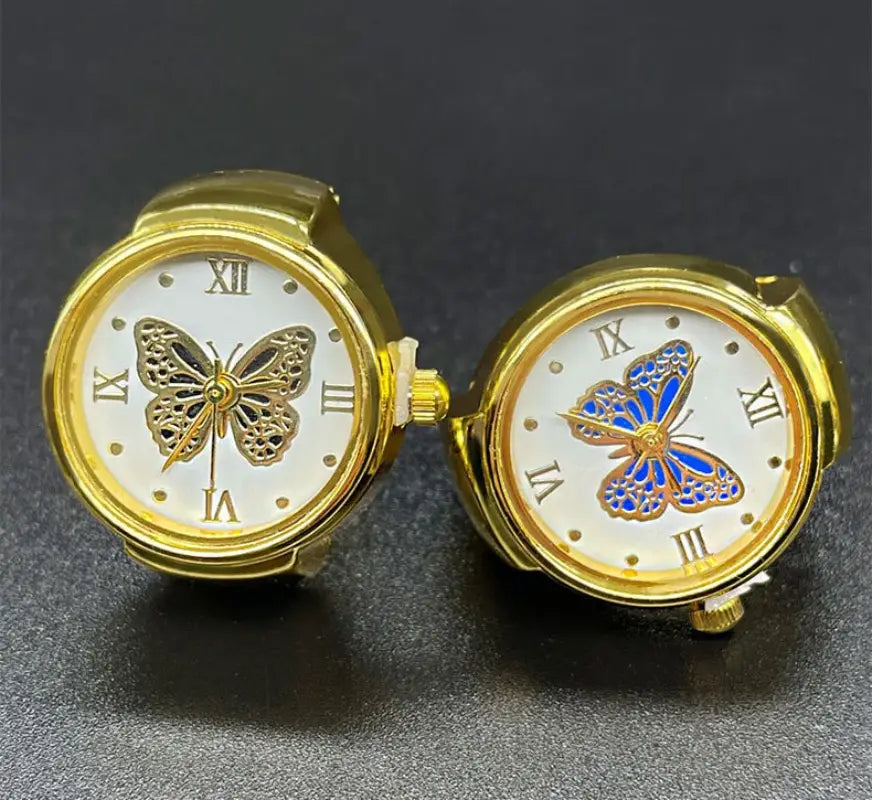 Two gold-toned stainless steel pocket watches featuring delicate butterfly designs on white faces, one with black filigree and the other with vibrant blue enamel, from the gold butterfly watch ring stainless steel cute jewelry collection.