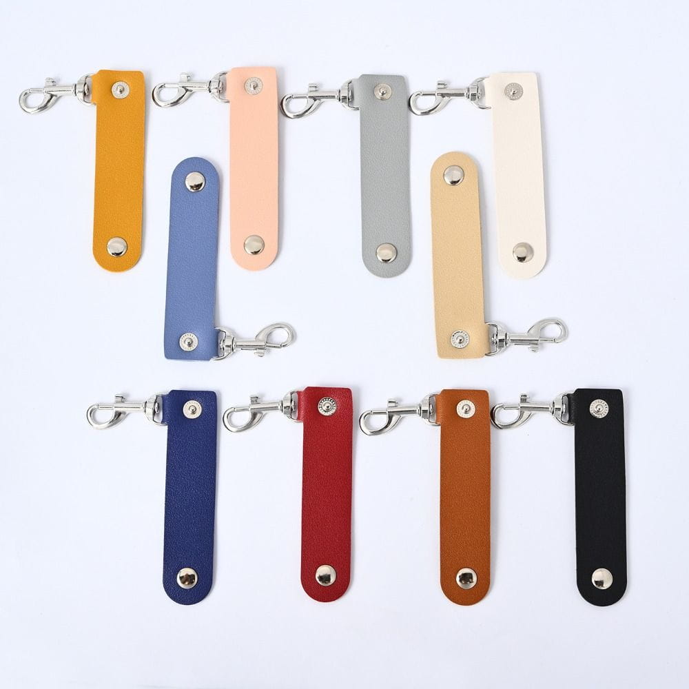 Eine Sammlung farbenfroher Pu-Leder-Schlüsselanhänger-Anhänger mit Anti-Verlust-Autoschlüsselriemen in Orange, Blau, Pink, Grau, Beige, Rot, Braun und Schwarz.