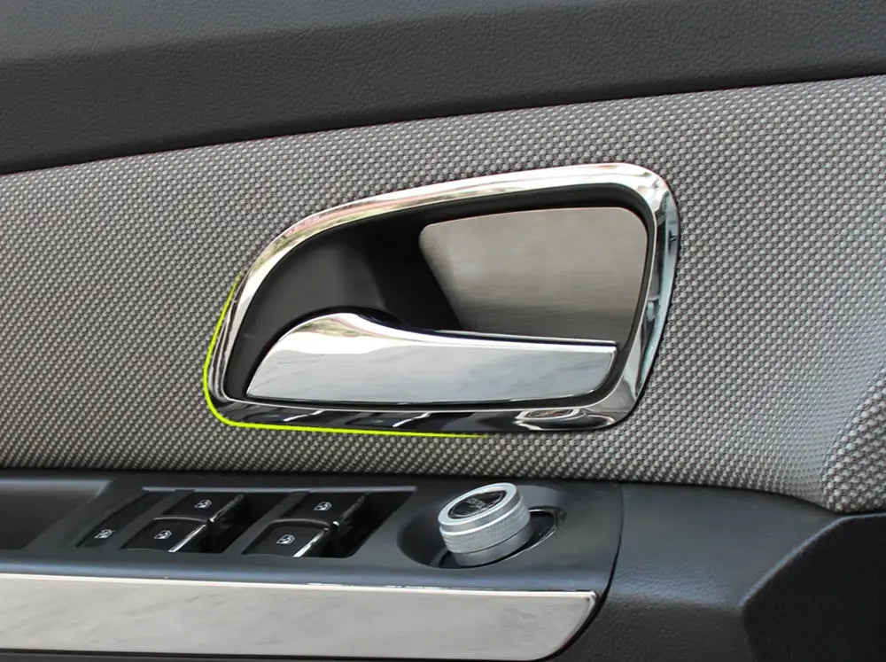 Manija de la puerta con acabado en cromo y diseño curvo y elegante para el interior de Chevrolet Cruze 2009-2014, colocada sobre una tela gris texturizada.