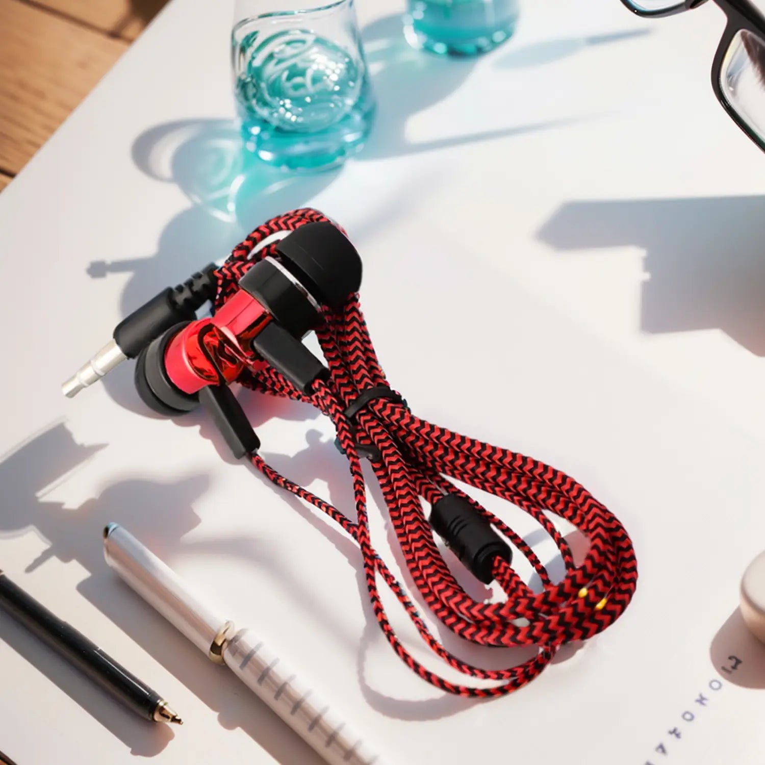Rote und schwarze geflochtene Bass-Stereo-Kopfhörer für den In-Ear-Bereich mit 3,5-mm-Klinkenstecker und einem glänzenden roten Akzent an der Inline-Lautstärkeregelung.