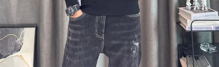 Jean en denim noir déchiré avec surpiqûres blanches et un aspect légèrement délavé et porté, associé à un pull-over en maille à empiècement contrastant pour homme, manches longues