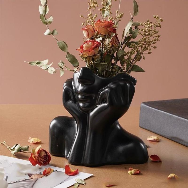 Black ceramic vase shaped like a reclining figure holding its head designed as an abstract face makeup brush holder and decorative ceramic vase.