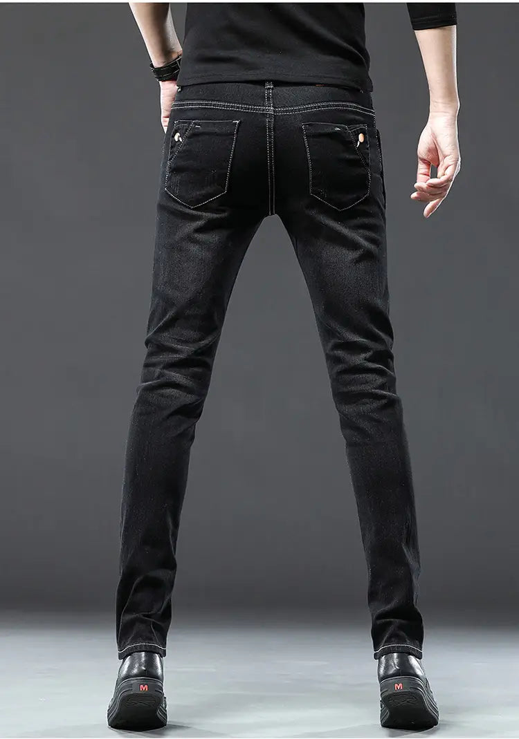 Jeans en denim à coupe slim noire avec surpiqûres discrètes et design classique de poche arrière, montrés de dos, dans un style de jeans slim vintage extensibles pour hommes en lavage gris.